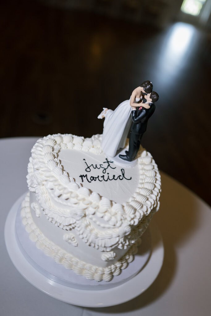 Small heart shaped wedding cake with bride and groom figurines kissing