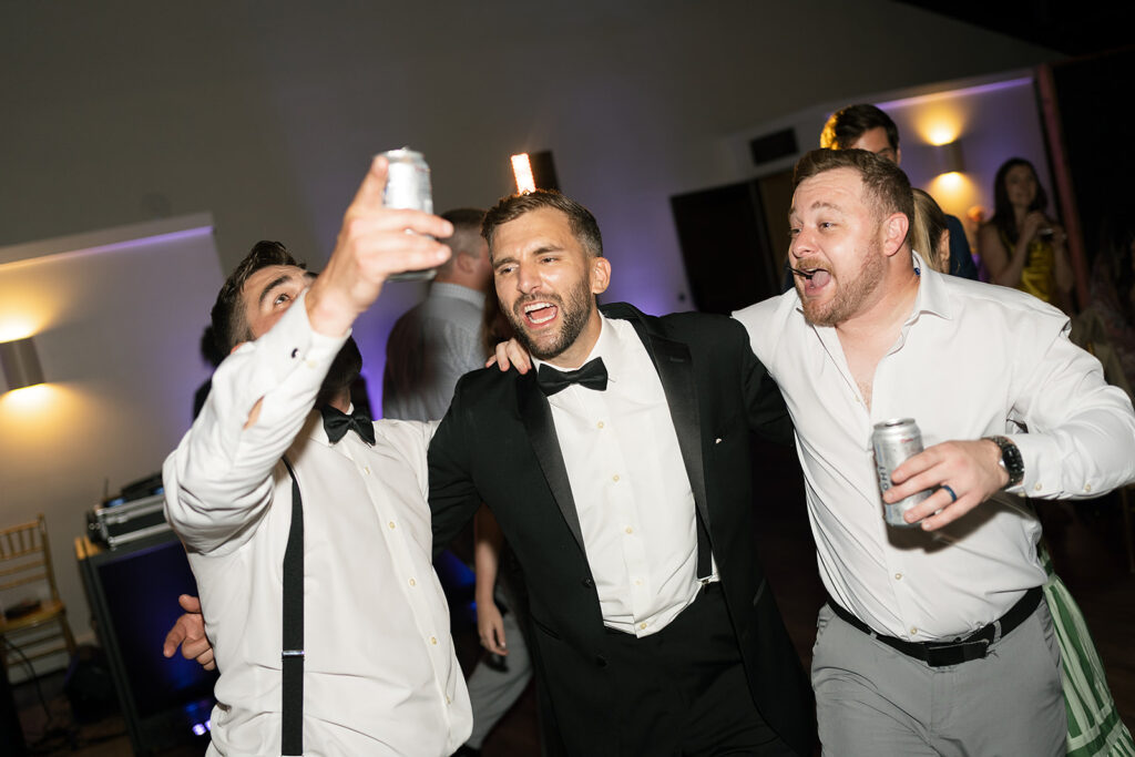 Groom dancing with friends on the dance floor