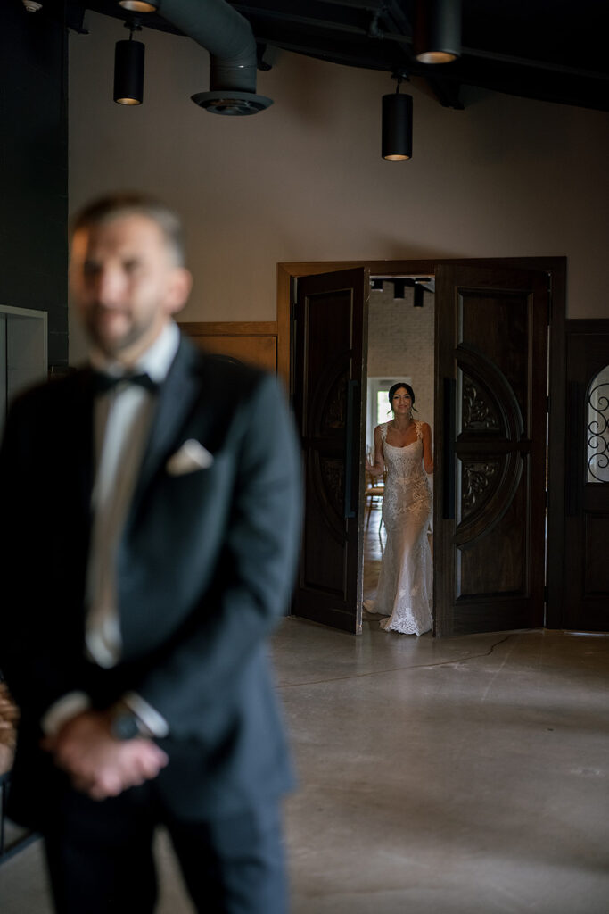 Bride walking into the room just before sharing a first look with her groom
