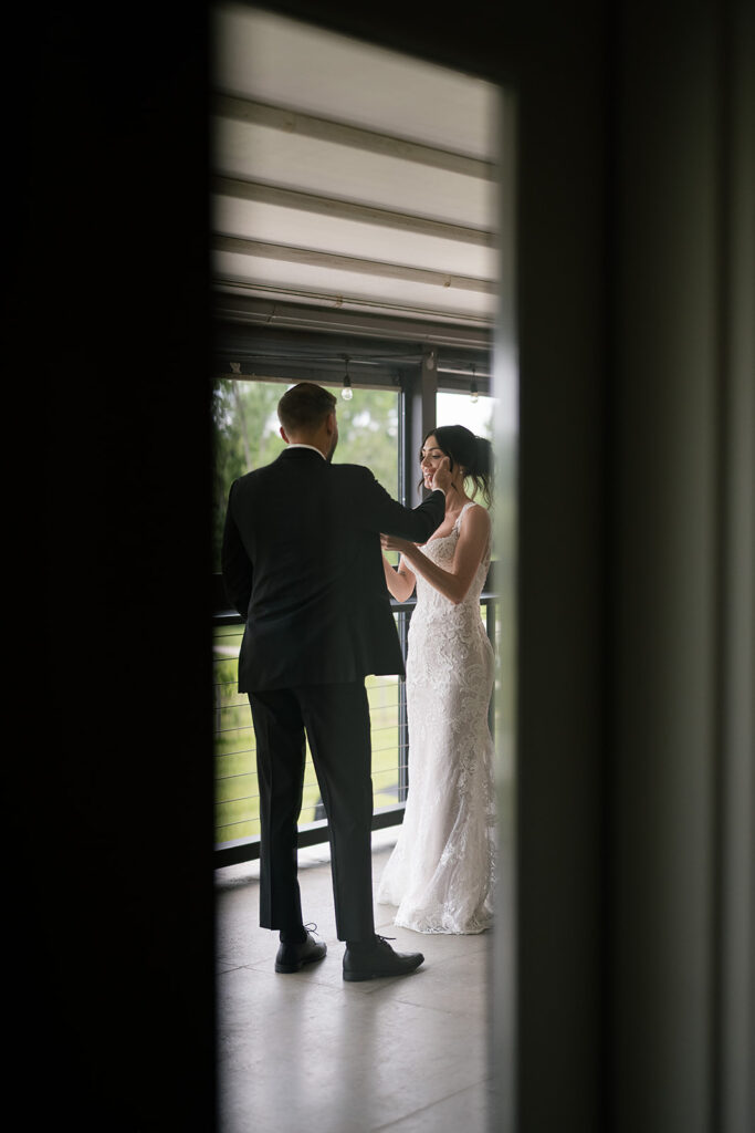 Groom wiping tears away from his brides cheek during their first look