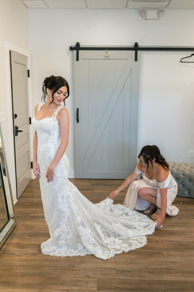 Bridesmaid helping bride with her dress