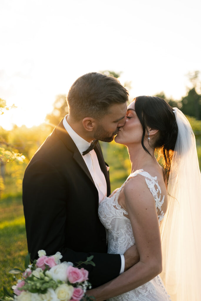 Bride and groom kissing during their outdoor golden hour portraits at Daniel's Vineyard in Indiana