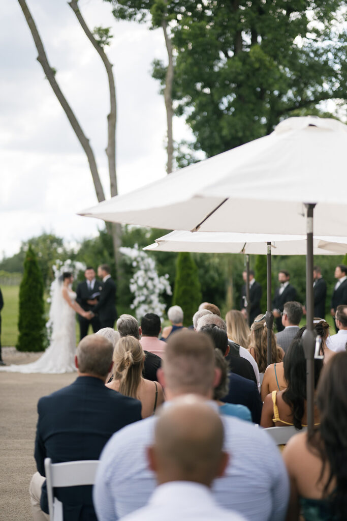 Bride and groom holding hands under floral arbor at Daniel’s Vineyard Ceremony Pad