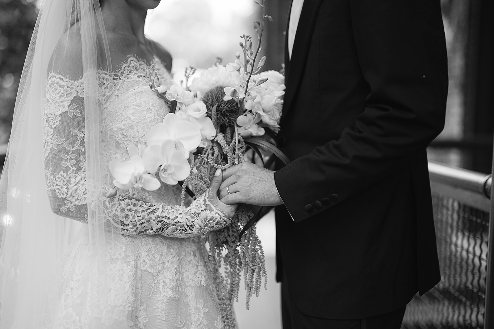 Black and white close up shot of a bride and groom holding hands