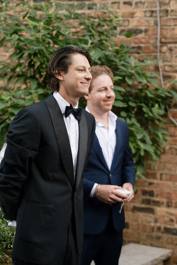 Groom smiling at the altar as guests look on during the ceremony.