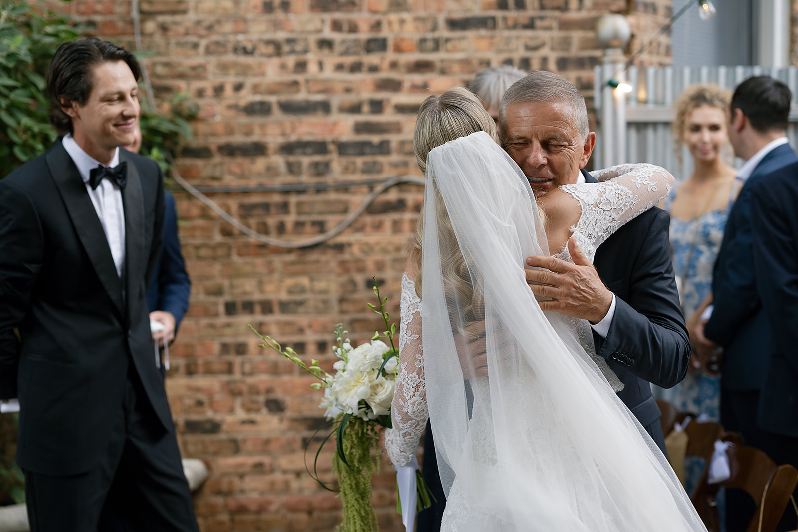Father of the bride hugging his daughter at the altar