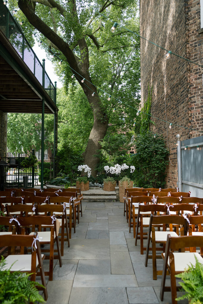 Outdoor ceremony space at Firehouse Chicago with rows of wooden chairs, brick walls, and ivy-covered backdrop.
