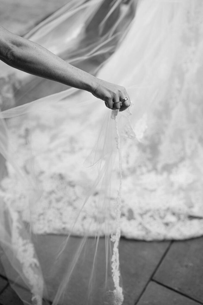 Black and white photo of the bridesmaid adjusting the brides veil during the ceremony