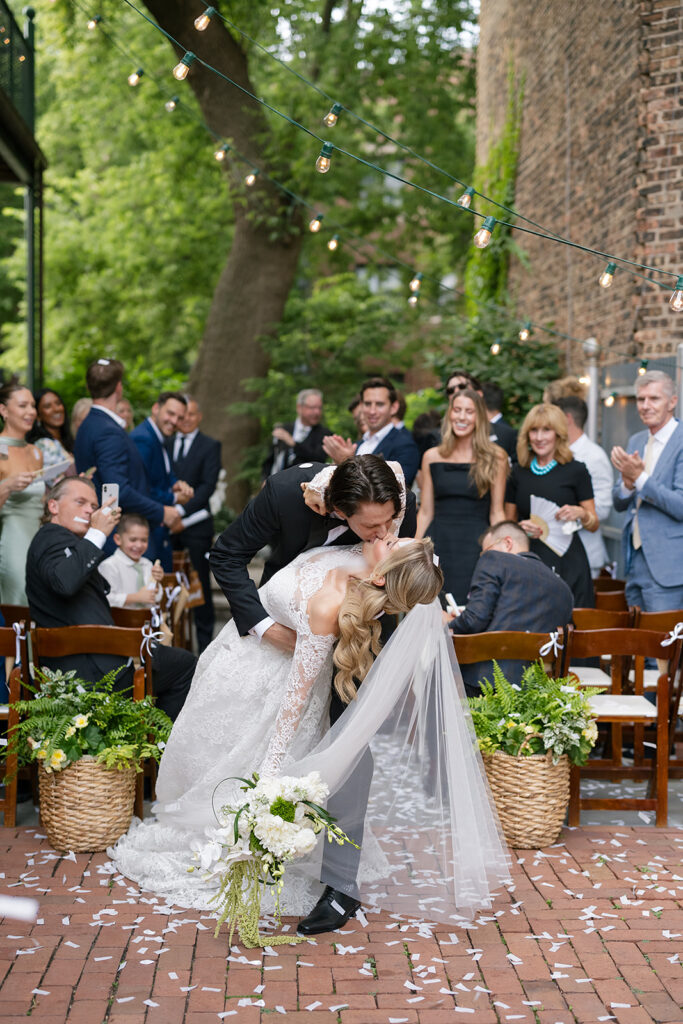 Bride and grooms end of aisle dip kiss after their Chicago Firehouse micro wedding ceremony 