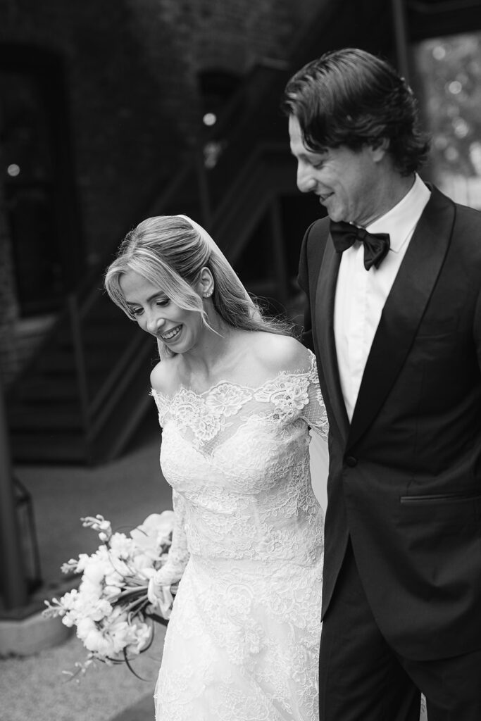 Black and white candid photo of a bride and groom walking away from the wedding ceremony as husband and wife
