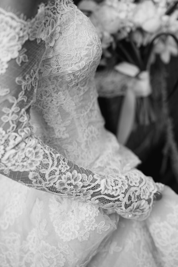 Close up black and white photo of a bride walking showcasing her stunning lace wedding dress