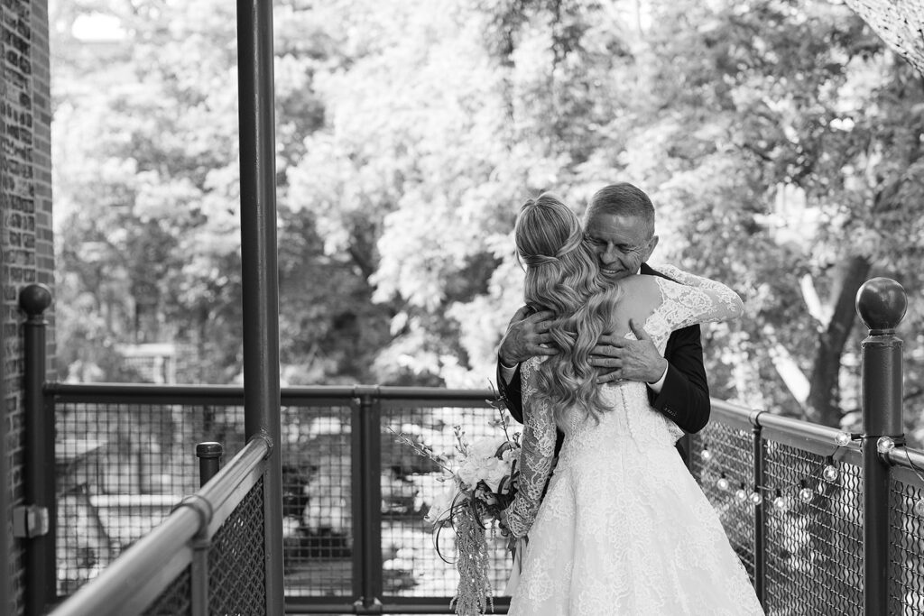 Black and white photo of a bride and her father hugging