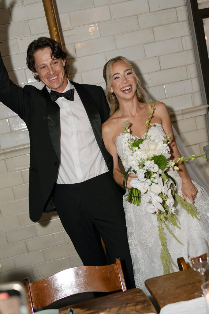 Bride and groom smiling as guests clap during their grand entrance