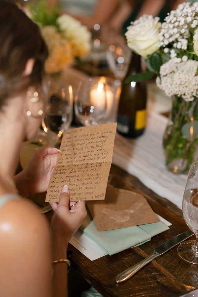 Guest reading a handwritten note from the couple at the reception dinner table.