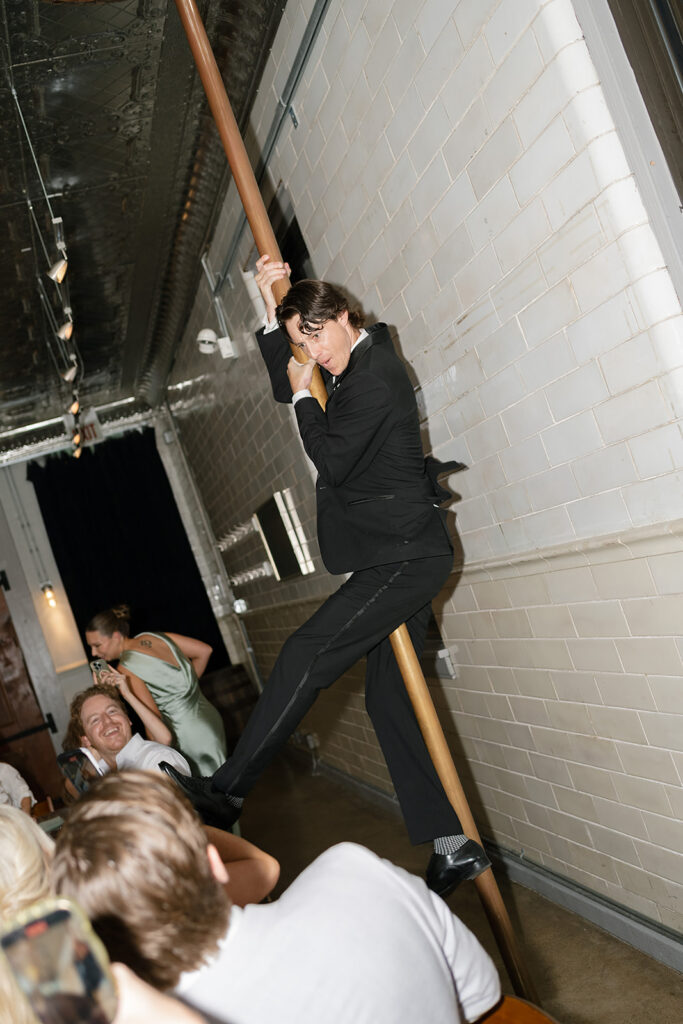 Groom in tuxedo sliding down the fire pole into the reception at Firehouse Chicago.