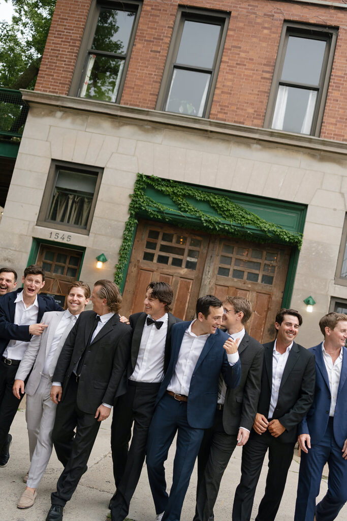 Groom laughing with groomsmen lined up outside Firehouse Chicago.
