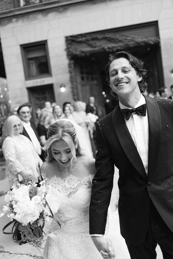 Black and white candid of bride and groom laughing during their wedding exit.